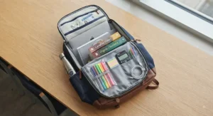 Flat lay view of a multi-pocket backpack for university students showing organized compartments for school supplies.